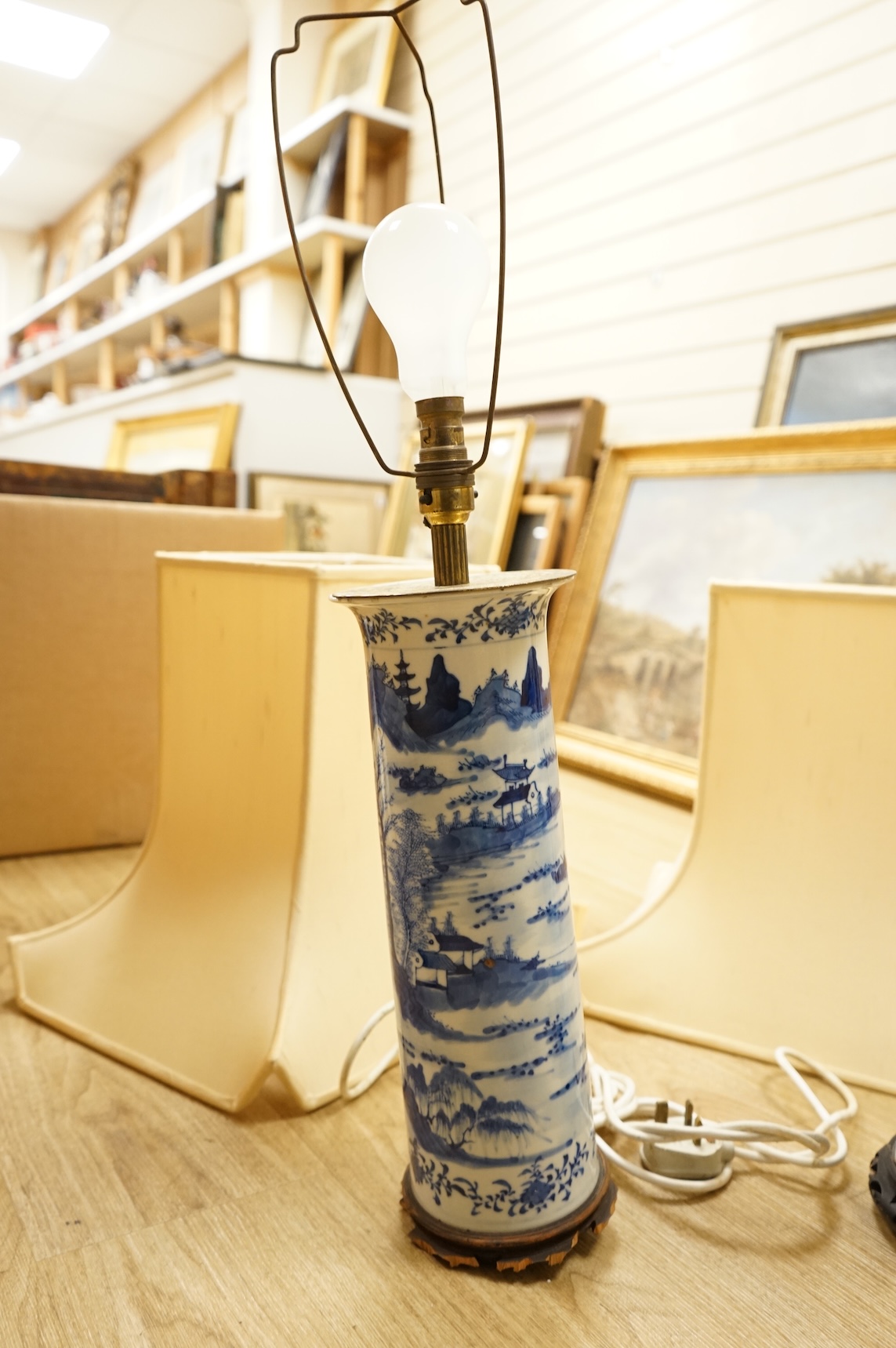A pair of tall Chinese blue and white ‘landscape’ sleeve vases, c.1900, drilled and mounted as lamps with shades, 39cm high excluding the fitting